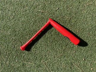 Red Apache hinged swing trainer bat angled at the hinge on turf