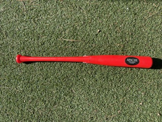 Red Apache swing trainer bat lying on turf