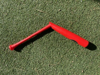 Red Apache hinged swing trainer bat bent at the hinge on turf